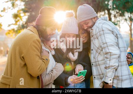 Group of young friends using cell phones outdoors in winter. Stock Photo