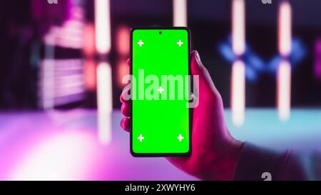 POV View of a Video Game Player Holding a Smartphone with Green Screen Mock Up Display. First Person View of a Man Holding a Device in Stylish Neon Room. Template for App, Software, Website Promotion Stock Photo