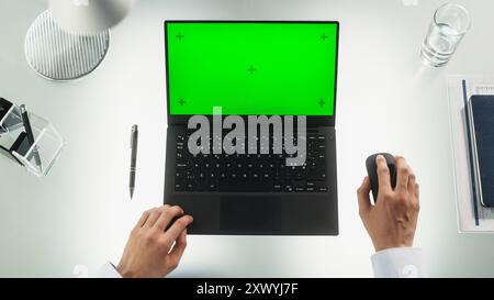 Anonymous Office Worker Typing on a Laptop Computer with Mock-Up Green Screen Chromakey Display with Motion Tracker Placeholders. Manager Corresponding with Business Partners by Email. Top Down View Stock Photo