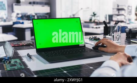 Anonymous Engineer Working in Lab on a Laptop Computer with Mock Up Green Screen Chromakey Display with Motion Tracker Placeholders. Photo Template for Industrial Content Creation and Presentation Stock Photo