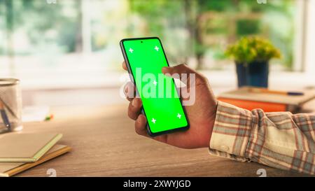 Anonymous Man Holding a Smartphone Device, Reading Articles on Mobile Phone with Green Screen Mock Up Display. Photo Template with Placeholder for Digital Marketing and Business Promotions Stock Photo