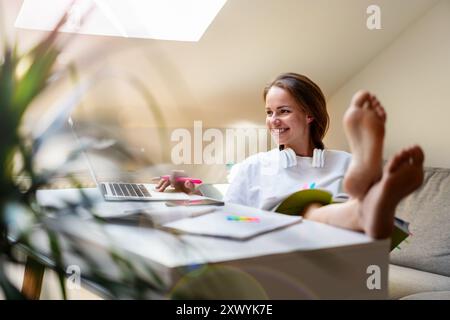 Young woman student wearing white t-shirt woman studying at a desk at home. Stock Photo