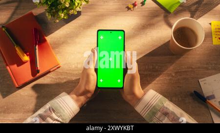 Office Worker Holding a Modern Mobile Phone in Front of a Camera. Smartphone with Green Screen Chroma Key Template for Digital Marketing, Promotion of Online Services, App, Software, Media Campaigns Stock Photo