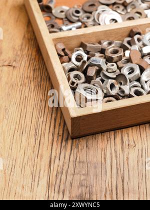 Old rusty bolts and nuts in a wooden box on a workbench Stock Photo