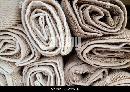 Rolled light-colored carpets in a store, close-up. Selection of carpets, carpet store. Stock Photo
