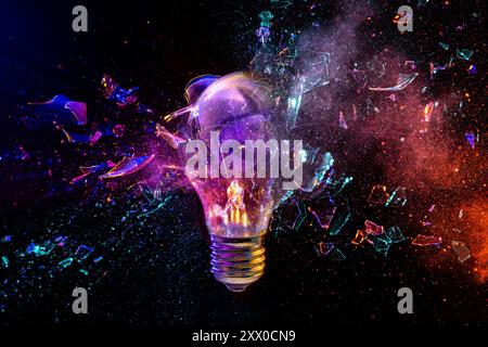 Light bulb is exploding while emitting colorful powder on a black background Stock Photo