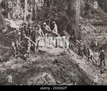 World War II. Bougainville campaign (1943-1945). Part of the Solomon Islands campaign of the Pacific Theater. Pretty rugged. A Marine wounded in the Bougainville fighting is carried to a field dressing station over a rough hewn trail. The sand and mud roadway required seven husky Leathernecks to carry the stretcher. Stock Photo