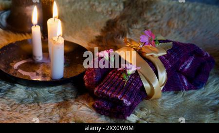 Christmas present - hand knit socks. Candles on a sheepskin. Stock Photo