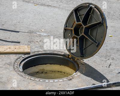 Open manifold manhole cover with hinge fastening Stock Photo