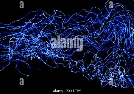 A long exposure photograph. Light Painting Photography - swirly waves of neon blue electric light against a black background Stock Photo