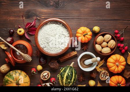 Dark wooden table with pumpkins and baking supplies, flour, honey, nuts. Stock Photo