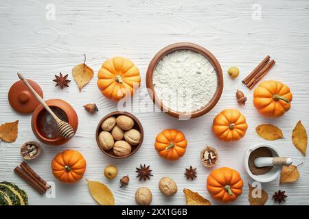 Light wooden table with pumpkins and baking supplies, flour, honey, nuts. Stock Photo