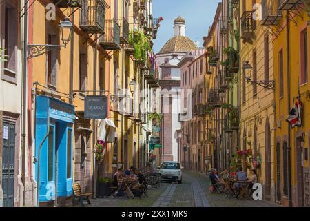 View along cobbled Corso Vittorio Emanuele II in the historic Sa Costa district, colourful tiled dome of the Cathedral prominent, Sardinia Stock Photo