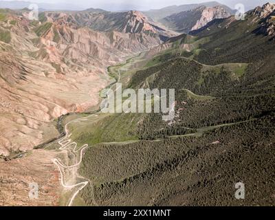 Aerial view of a winding mountain road curves, Kalmak Ashuu Pass, through lush greenery in Kyrgyzstan, Central Asia, Asia Stock Photo