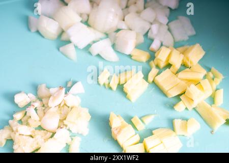 Chopped onion, pineapple and garlic on a blue cutting board. Ingredients for a traditional dish. High quality photo Stock Photo