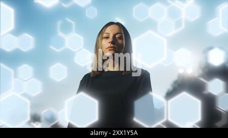 Young female soccer player standing confidently against a backdrop of glowing hexagonal patterns and light trails. Ideal for illustrating themes of sp Stock Photo