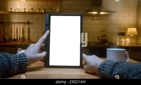 Point of view shot: Close-up of man using white mock-up screen digital tablet computer on the table. Man scrolls and taps on tablet computer in modern Stock Photo
