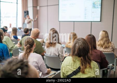 Conference room filled with attentive participants listening to presenter delivering engaging lecture on various topics. Learning atmosphere captured in modern professional environment. Stock Photo