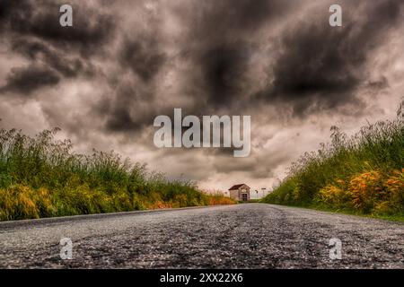 Grey storm clouds over a Small church at the end of a straight road, San Giuliano Vecchio, Alessandria, Piedmont, Italy Stock Photo