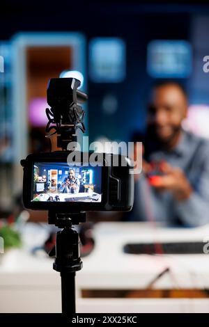 Focus on professional video production gear used for capturing footage of media star in blurry background filming tech reviews for his online channel, showcasing computer peripherals Stock Photo