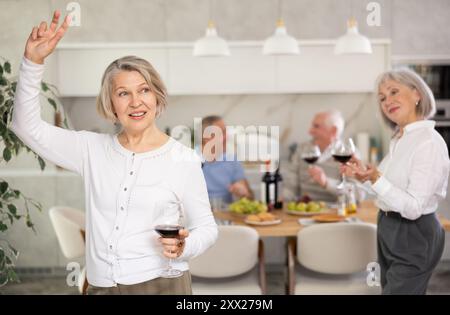 Senior men and women have fun dancing during house party. Stock Photo