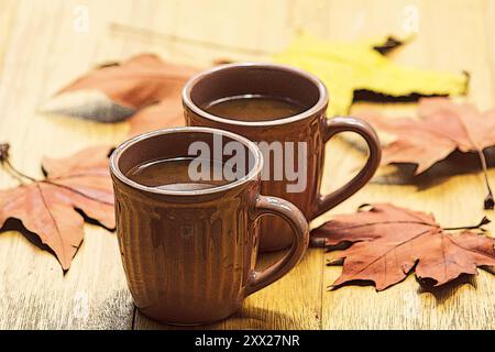 Two cups of coffee among autumn leaves on a table Stock Photo