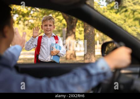 Father waving hand to his son near school, view from inside the car Stock Photo