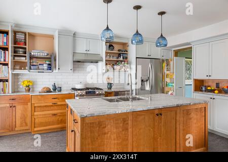 New kitchen with blue gray upper cabinets and red birch lower cabinets and island with doors open Stock Photo