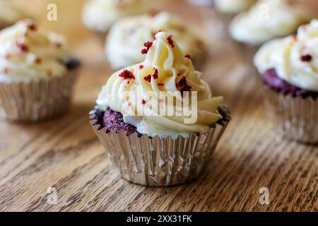 Red velvet cupcakes in silver foil on a wooden table. Stock Photo