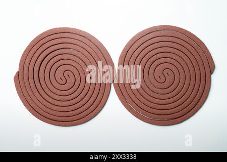 Mosquito coils are shown on a white background. The objects are circular and have a spiral design. Concept of movement and energy, as if the objects a Stock Photo