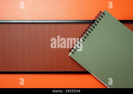 A green spiral notebook sits on top of a black metal frame. The notebook is open to a blank page, ready for writing Stock Photo
