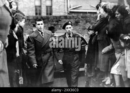 File photo dated January 1953 of Leading-Aircraftman Iain Hay Gordon in uniform, being led to a court in Belfast, where he was found guilty of murdering judge's daughter Patricia Curran in Co Antrim, in November 1952. In November 2000, at 68-years-old, Iain Hay Gordon was found to have been wrongly convicted in one of Northern Ireland's most notorious murders by the Northern Ireland Court of Appeal in Belfast. Issue date: Thursday August 22, 2024. Stock Photo