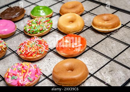 A tray of assorted mini donuts with sprinkles and frosting. The mini donuts are of different colors and flavors, and they are arranged in a grid patte Stock Photo