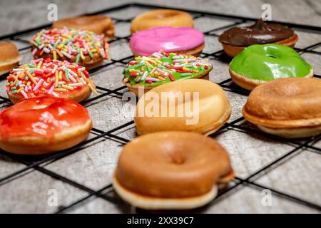 A tray of assorted mini donuts with sprinkles and frosting. The mini donuts are of different colors and flavors, and they are arranged in a grid patte Stock Photo