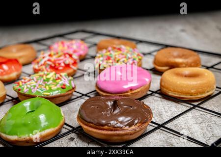 A tray of assorted mini donuts with sprinkles and frosting. The mini donuts are of different colors and flavors, and they are arranged in a grid patte Stock Photo