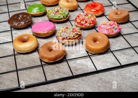 A tray of assorted mini donuts with sprinkles and frosting. The mini donuts are of different colors and flavors, and they are arranged in a grid patte Stock Photo