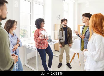 Multiracial group of students or colleagues standing together, talking and sharing work ideas. Stock Photo