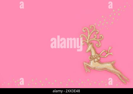 Christmas Eve gold reindeer tree bauble ornament on pink background with gold sparkle decorations. Magical fantasy symbol for Xmas Yule. Copy space. Stock Photo