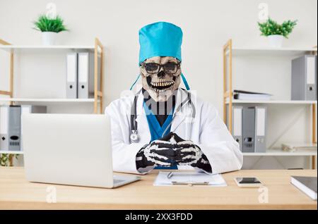 Portrait of a funny evil doctor in a scary skeleton costume at work in the office Stock Photo