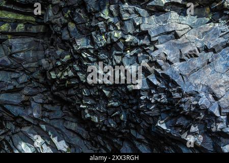 The image is of a rock formation with a dark blue color. The rocks are jagged and rough, giving the impression of a harsh and rugged environment. Scen Stock Photo