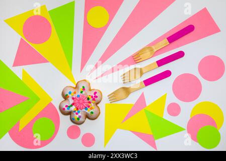 Flower shaped donut with wooden spoons on a multicolored grafic background Stock Photo