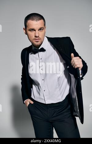 A man in a tuxedo stands confidently, adjusting his jacket with a sophisticated air. Stock Photo