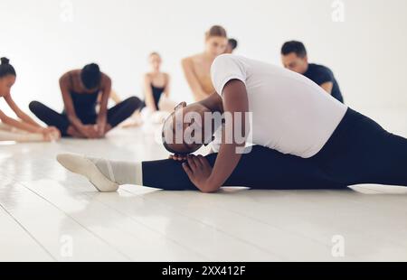 Boy, ballerina and split for stretching in class with training, muscle and start lesson at dance school. Person, dancer and warm up in studio, floor Stock Photo