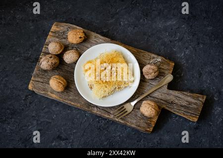 Turkish dessert homemade kadayif on plate with walnuts, Shredded dough baked in syrup topped with crushed nuts, Turkish delight Stock Photo