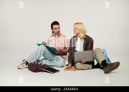 Two young queer students are sitting on the floor, studying together. Stock Photo