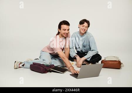 Two young queer students collaborate on a laptop in a studio setting. Stock Photo