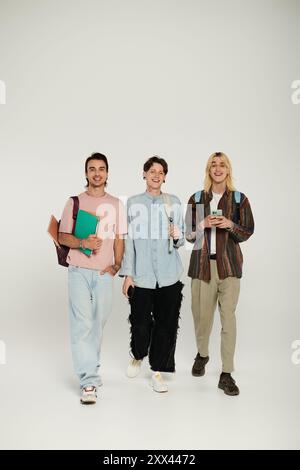 Three young adults walk casually towards the camera in a studio setting. Stock Photo
