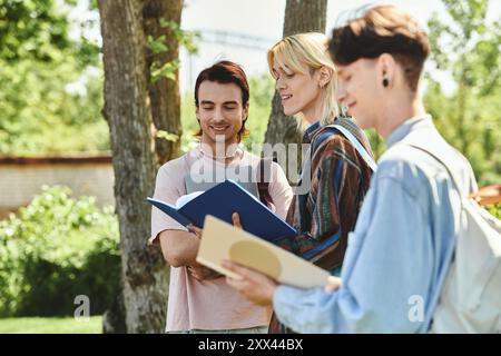 Three young friends, dressed casually, study together outside on a sunny day. Stock Photo