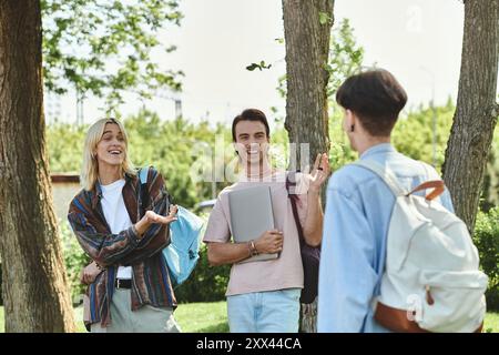 Three young friends, casually dressed, chat and laugh together outdoors on a sunny day. Stock Photo
