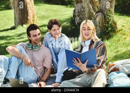 Three young friends, dressed casually, share a laugh while reading a book outdoors. Stock Photo